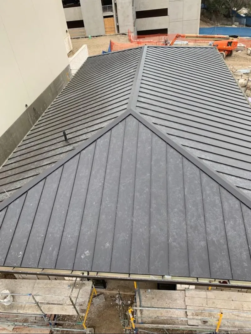 Commercial metal roof construction with crane equipment in Anniston